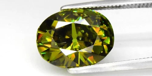 Large oval green demantoid gemstone with faceted light green and dark green inclusions, held on a white background.