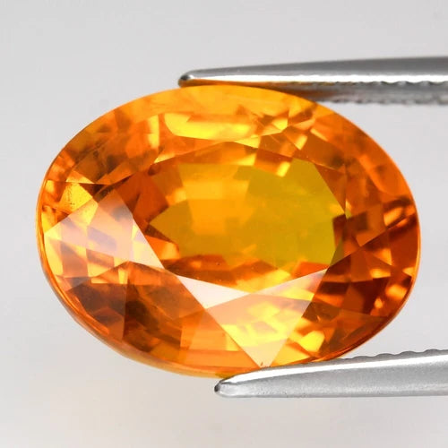 Big oval yellow sapphire with 8.78ct, Thailand origin, held by silver-tone tweezers against a white background.